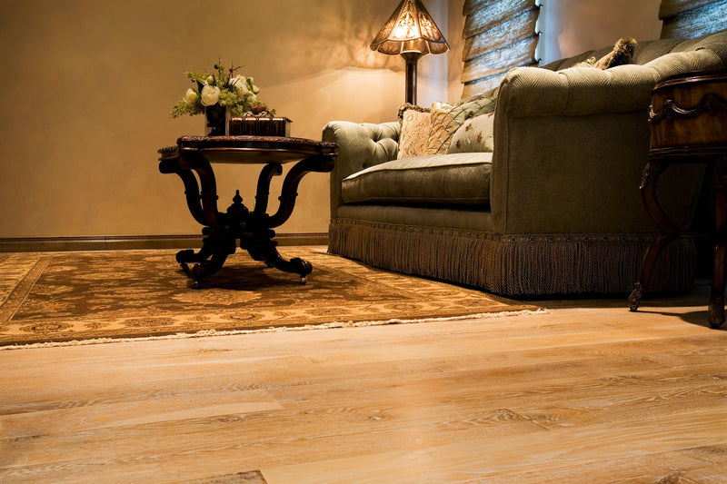 A living space with antique furniture, a wooden table, an old style sofa, and our reclaimed wood flooring.